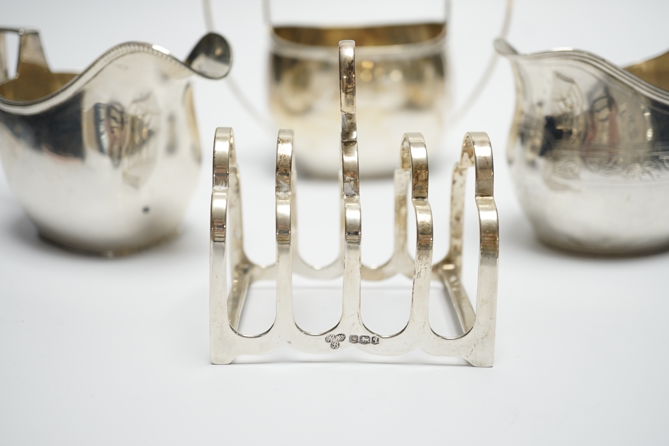 A George III engraved silver cream jug, London, 1808, height 82m, a George V silver cream jug and matching sugar bowl, and a George V silver five bar toast rack, 15.4oz.
